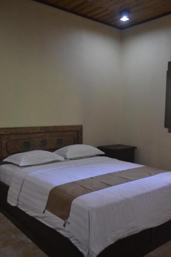a bedroom with a large bed with white sheets and pillows at hotel batukaras kalaras in Batukaras