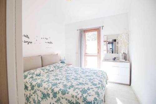 a white bedroom with a bed and a window at Casa Pace Stintino in Stintino