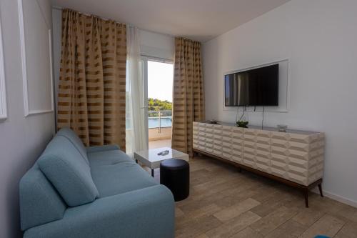 un soggiorno con un divano blu e una TV a schermo piatto di Perla Resort a Rogoznica (Rogosnizza)