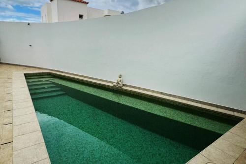 une piscine d'eau verte à côté d'un mur blanc dans l'établissement Costa Adeje Villa Private pool Panoramic Views, à Adeje