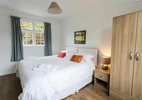ein Schlafzimmer mit einem weißen Bett und einem Fenster in der Unterkunft Old Mill Cottage in Gweek