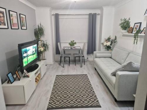 a living room with a couch and a tv and a table at Flat in Hamilton, South Lanarkshire in Hamilton