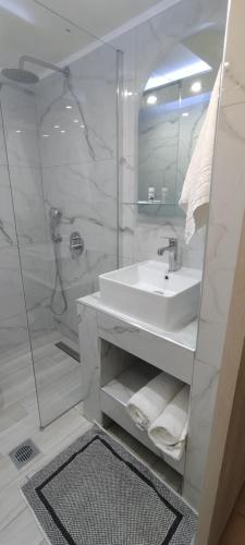 een witte badkamer met een wastafel en een douche bij Sweetmar guestRooms-ground floor in Kos-stad