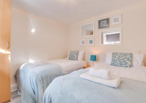 Un dormitorio blanco con 2 camas y una silla en Cuthbert Cottage, en Warenford