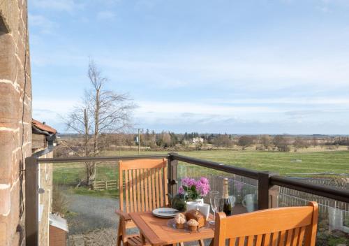 una mesa en un balcón con vistas a un campo en Cuthbert Cottage, en Warenford