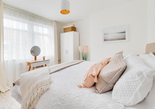 1 dormitorio blanco con 1 cama blanca grande con almohadas en Grace Cottage en Amble