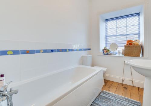 a white bathroom with a tub and a sink at Kirkside in Embleton
