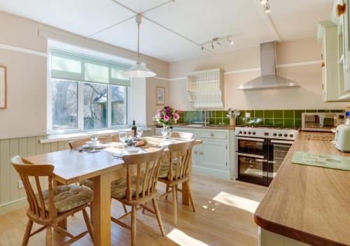 a kitchen with a wooden table and chairs in it at Coldburn Cottage in Kirknewton