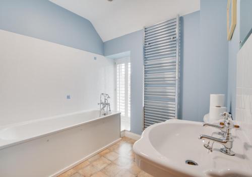 Baño blanco con lavabo y bañera en Dunsdale House, en Kirknewton