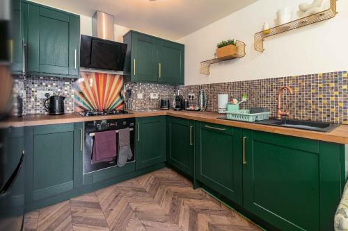a green kitchen with green cabinets and a sink at Ideal Lodgings In Openshaw in Manchester