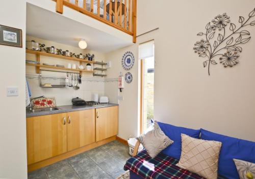 a living room with a blue couch and a kitchen at Bonny Barn in Harbottle
