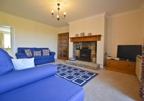 a living room with a blue couch and a fireplace at Beach View Cottage in Amble