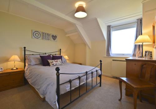 a bedroom with a bed and a window and a chair at Beach View Cottage in Amble
