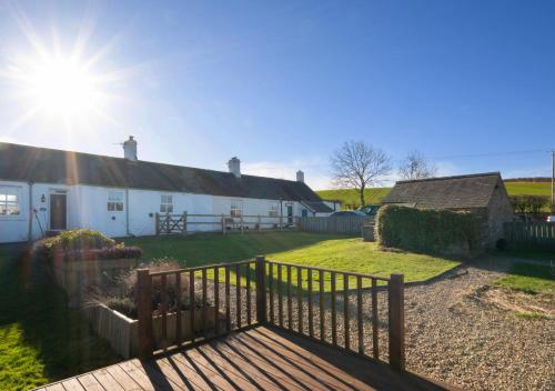 una casa blanca con una valla de madera delante de ella en Bede Cottage en Chatton