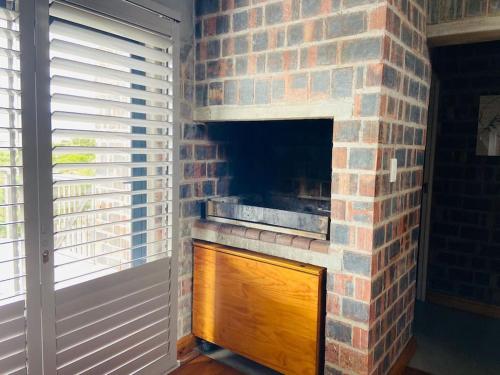 a brick fireplace in a room next to a window at Secure, luxurious with lovely views in Pringle Bay