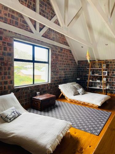 a room with two beds and a brick wall at Secure, luxurious with lovely views in Pringle Bay