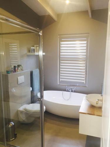 a bathroom with a tub and a toilet and a sink at Secure, luxurious with lovely views in Pringle Bay