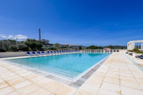 une grande piscine avec des chaises longues bleues dans l'établissement Maison Fab & Jo - Proche de lîle rousse, à Belgodère