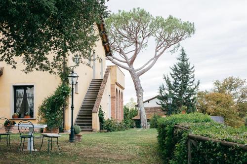 a yard with chairs and a tree next to a house at Agriturismo Bellavista in San Miniato