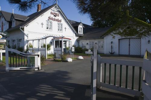 a white house with a gate and a fence at Aparthotel Friesenhof in Wenningstedt