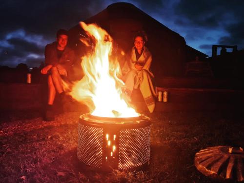 three people sitting around a bonfire at night at Acre & Shelter Yurt and Bell Tents at Bramham Horse Trials in Leeds