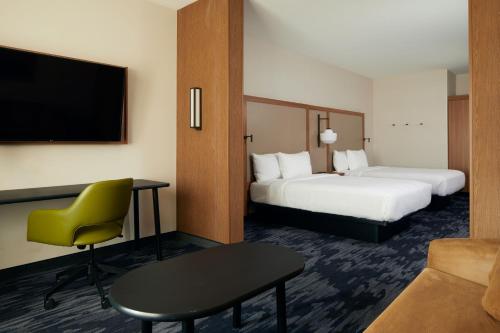a hotel room with two beds and a desk and a tv at Fairfield by Marriott Inn & Suites Palmdale West in Palmdale