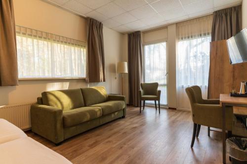 a hotel room with a couch and a desk at Hotel de Stoppelberg in Beekbergen