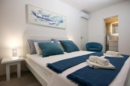a bedroom with a large white bed with blue pillows at Dalmatian stone house with swimming pool near Supetar in Supetar