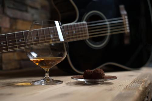 a glass of wine and a cookie on a table with a guitar at Hotel Vedig in Santa Caterina Valfurva
