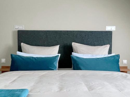a bed with blue and white pillows on it at The Green Rostock Apartment Hotel in Rostock
