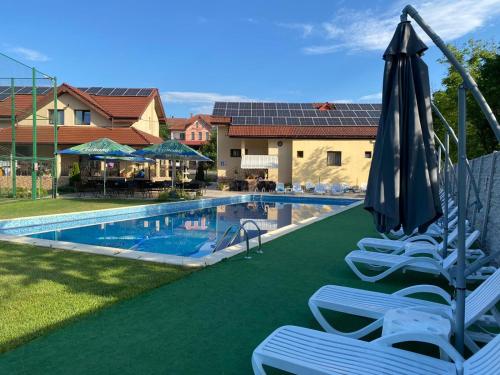 a swimming pool with lawn chairs and an umbrella at Complex Agroturistic Flori in Vaţa de Jos