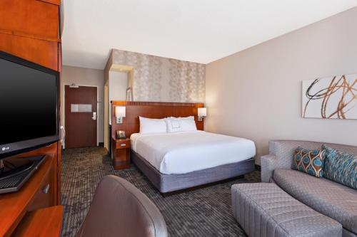 a hotel room with a bed and a couch at Courtyard by Marriott Fort Smith Downtown in Fort Smith