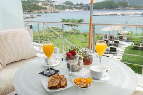 a white table with breakfast foods and glasses of orange juice at Tango Apartment On The Beach in Paleokastritsa