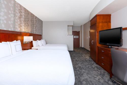 a hotel room with two beds and a flat screen tv at Courtyard by Marriott Fort Smith Downtown in Fort Smith