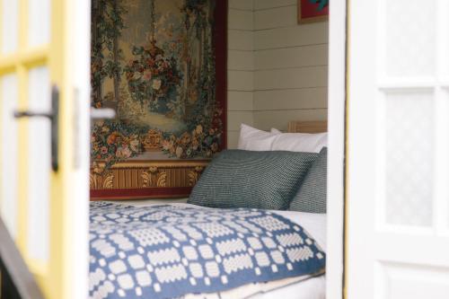 a bedroom with a bed with a tapestry on the wall at Beekeeper's Hut - Hawarden Estate in Hawarden