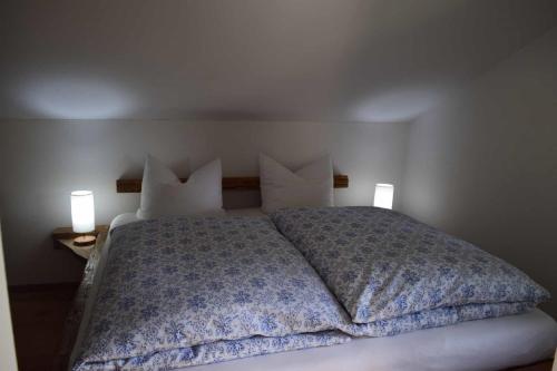 a bedroom with a bed with pillows and two lamps at Birken Chalet in Falkenfels