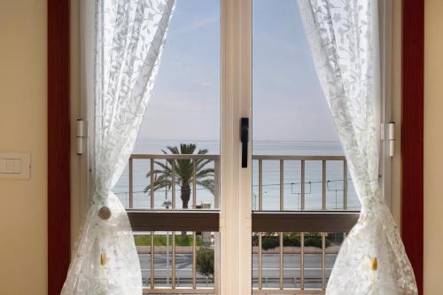 a window with curtains and a view of the ocean at Numero 7 in Borgio Verezzi