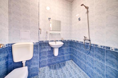 Baño de azulejos azules con aseo y lavamanos en Copacabana Hotel, en Ravda