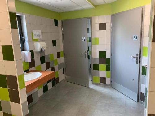 La salle de bains est pourvue d'un lavabo et de carrelage vert et blanc. dans l'établissement Les Lodges de la ViaRhôna - Tentes Lodges, à Virignin