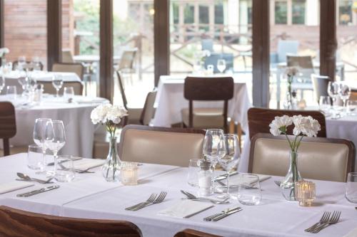 a table in a restaurant with white tables and chairs at Hampshire Court Hotel & Spa in Basingstoke