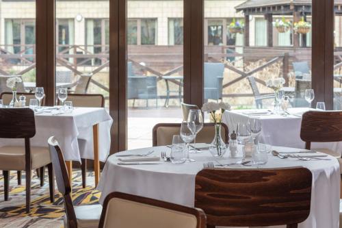 a dining room with tables and chairs with white tablecloths at Hampshire Court Hotel & Spa in Basingstoke