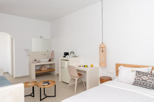 Ein weißes Zimmer mit einem Bett, einem Tisch und einem Schreibtisch. in der Unterkunft Ihthioessa Boutique Hotel in Astypalea-Stadt
