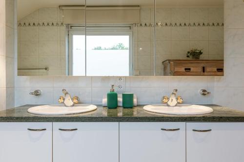 łazienka z 2 umywalkami i lustrem w obiekcie Guesthouse in the heart of the flemish ardennes w mieście Zwalm
