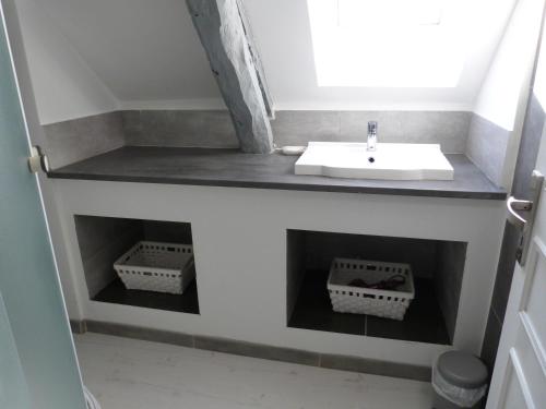 La salle de bains est pourvue d'un lavabo et de paniers sur le mur. dans l'établissement Gîte avec Piscine proche de St Cirq Lapopie, à Berganty