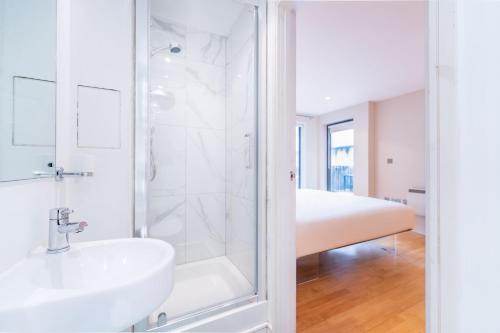 a white bathroom with a sink and a shower at Prince William Apartment in London