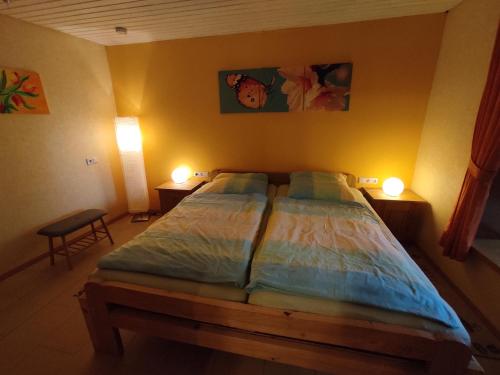 a bedroom with a bed with two lamps on the wall at Moselferienweingut Schaefer in Wintrich