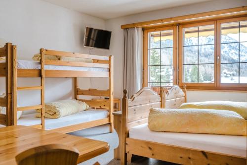 a room with three bunk beds and a table and a television at Aktiv Hotel & Spa Hannigalp in Grächen