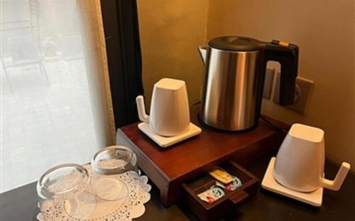 a coffee maker sitting on a wooden table with dishes at Hotel Fontaines du Luxembourg in Paris