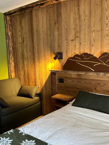 a bedroom with a bed and a chair and a lamp at L'Abreny in Brusson