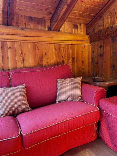 a red couch and two stools in a room at L'Abreny in Brusson
